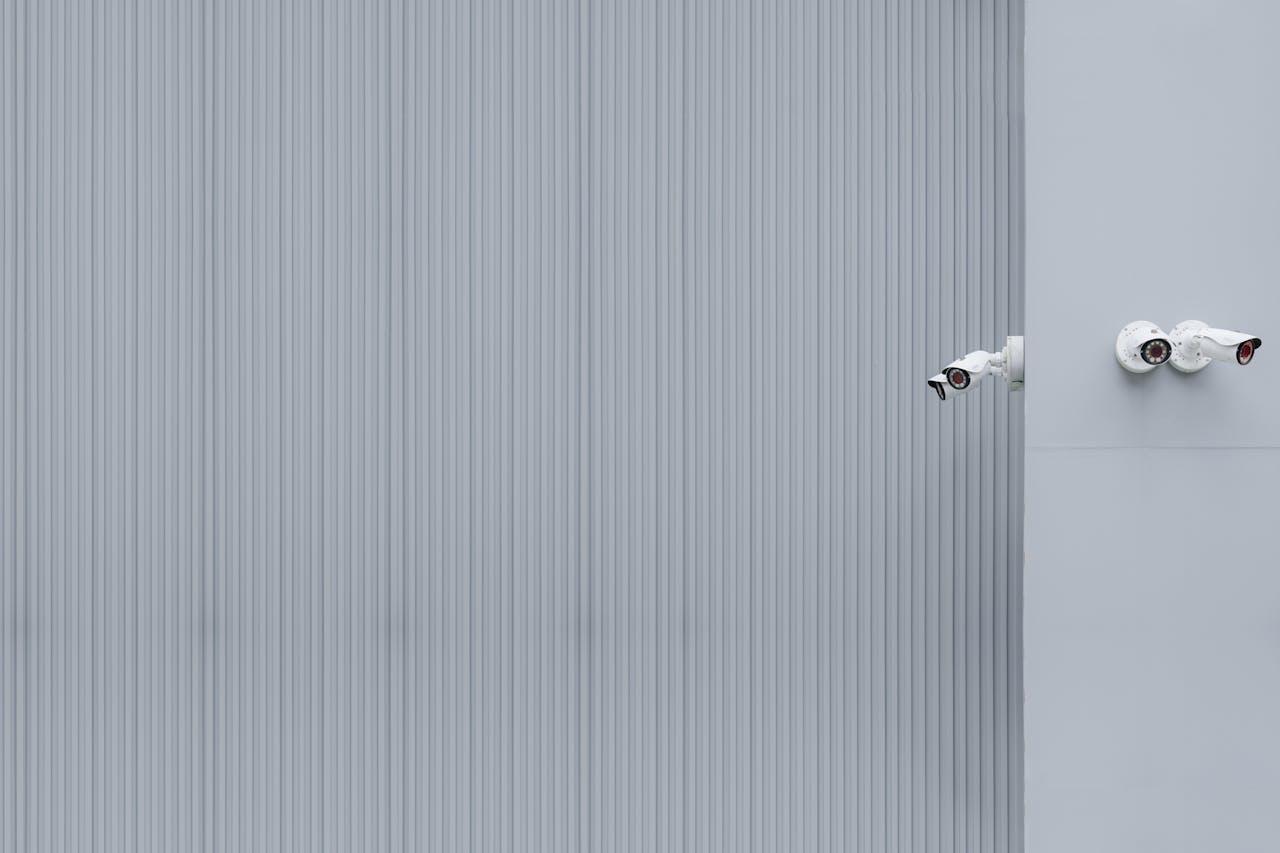 Two security cameras on a gray corrugated wall illustrating minimalism and surveillance.